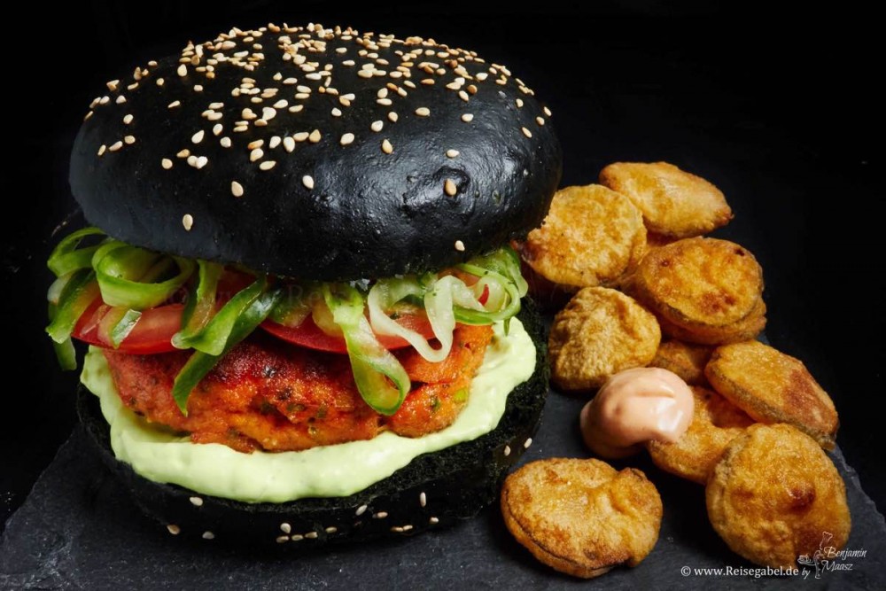 Burger mit Lachs, schwarzem Bun und fried Pickles
