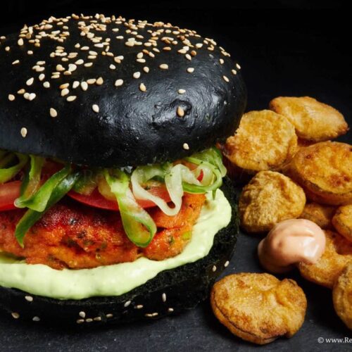 Burger mit Lachs schwarzem Bun und fried Pickles