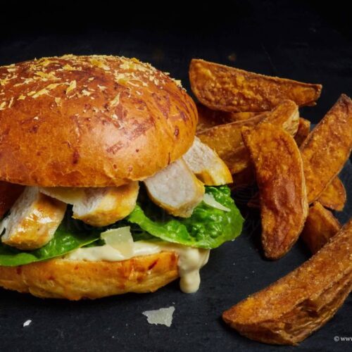 Caesar Hühnchen Burger mit Parmesan Bun und Wedges serviert
