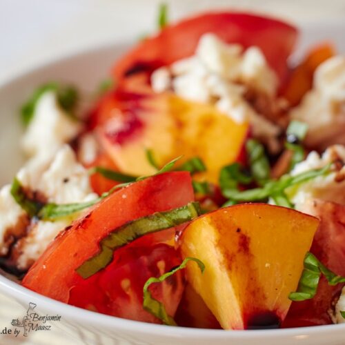 Tomaten Pfirsich Salat mit Mozzarella und Basilikum auf einer Platte serviert