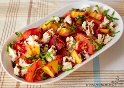 Tomaten Pfirsich Salat mit Mozzarella und Basilikum auf einer Platte serviert